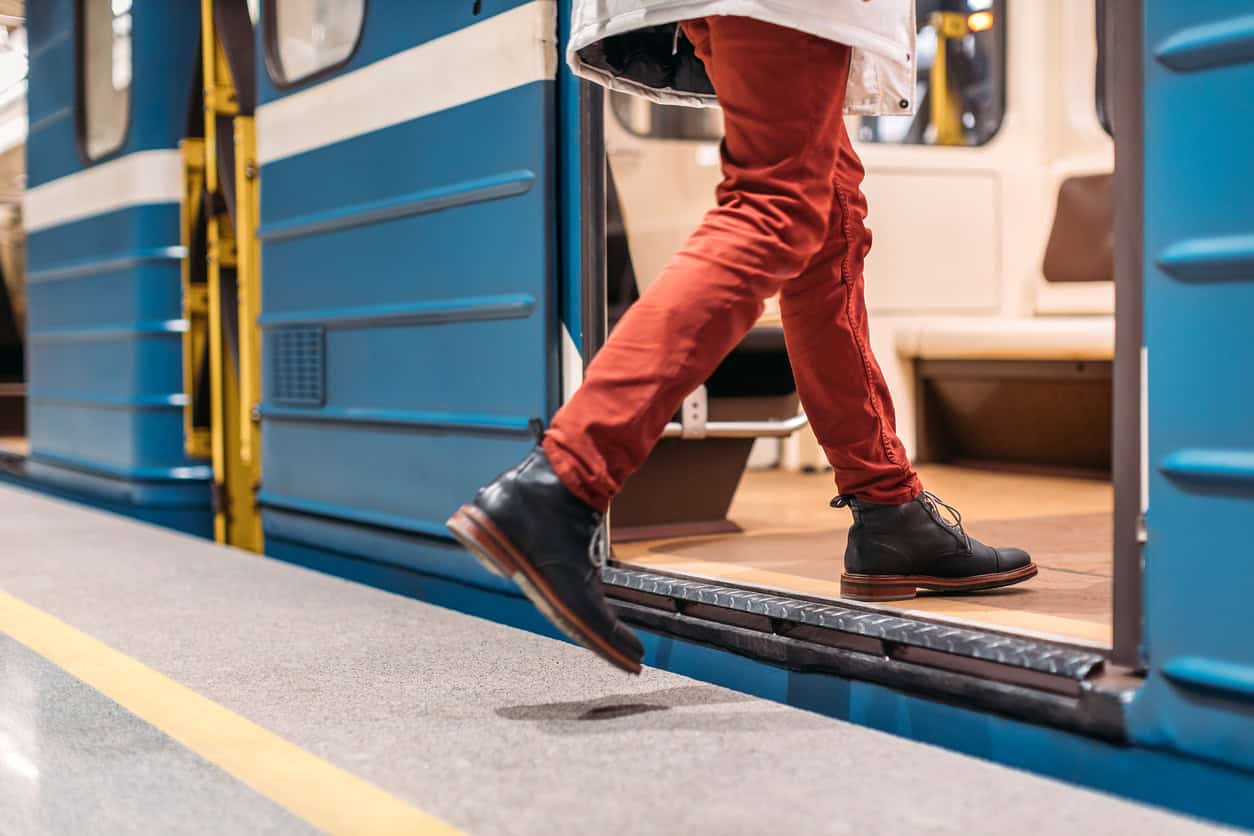 Person in black shoes, burgundy pants and white jacket runs into a subway train.