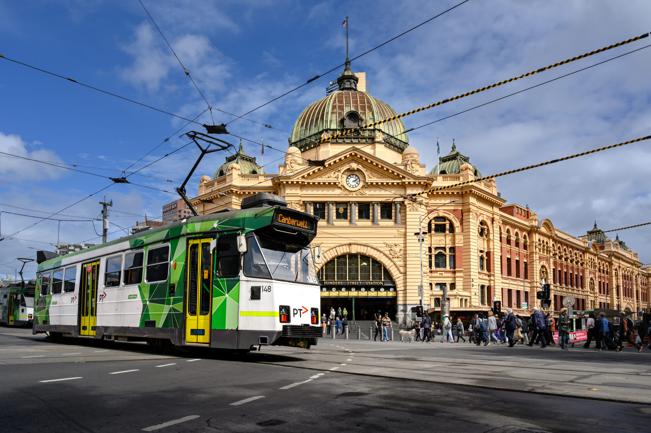 A modern tram and pedestrians Flinders Street Station in Melbourne.